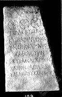 Gravestone, decorated on top with three roughly-carved rosettes in the shape of circles with stars of 6 double rays inside